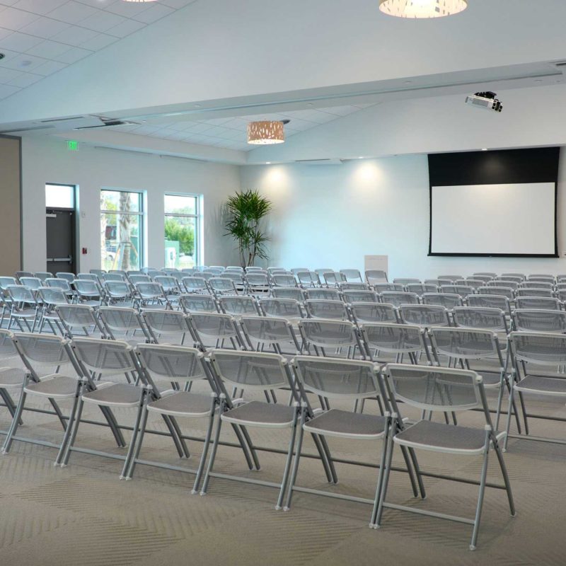 A conference room with rows of chairs and a projection screen.