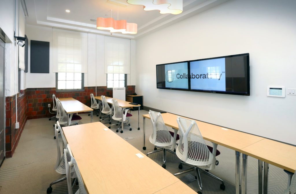 A conference room with a large screen on the wall.