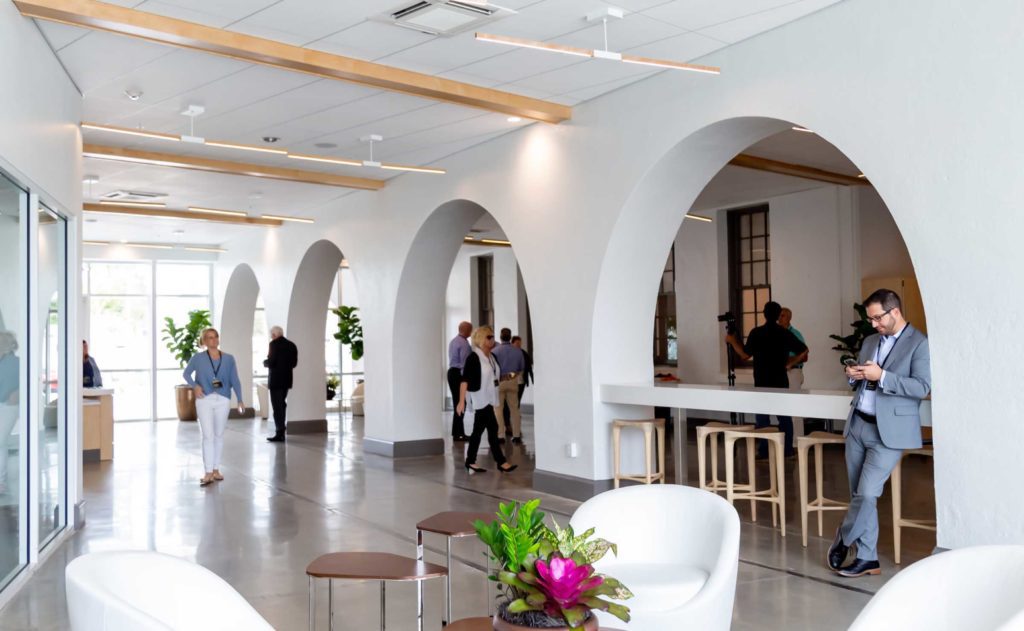 The lobby of an office building with white chairs and arches.