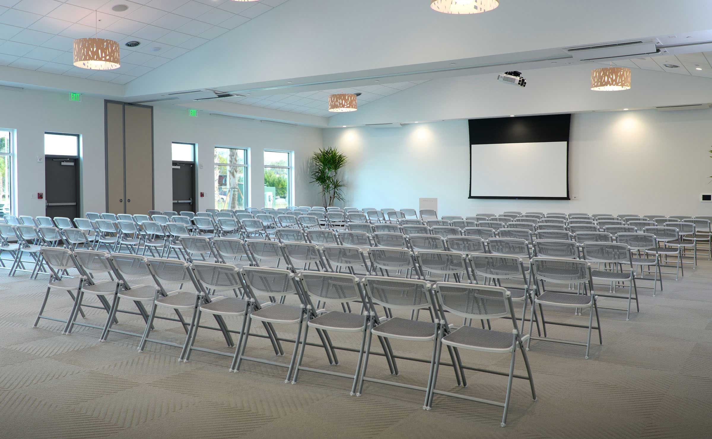 A conference room with rows of chairs and a projection screen.
