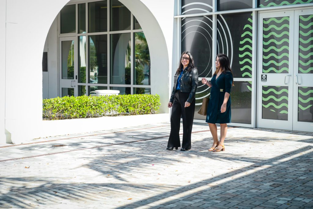 Two smiling staff members walking outside the entrance of Collaboratory.