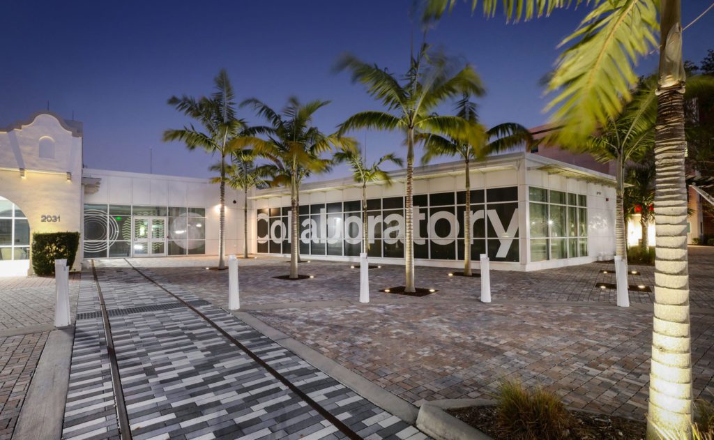 The entrance to a building at night with palm trees.