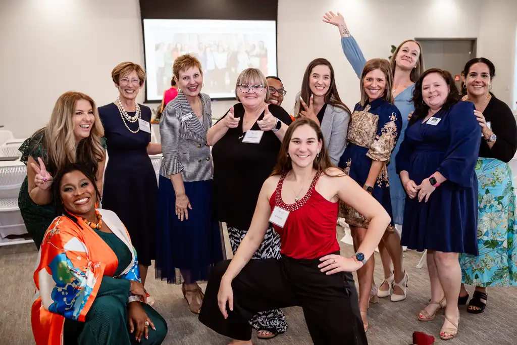 A diverse group of women posing for a group photo in a conference room.
